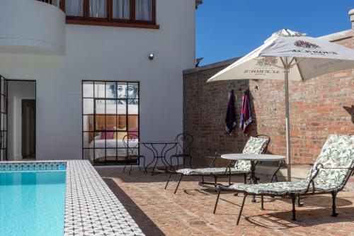 a patio with a table and an umbrella next to a pool at La Maison On Main Self-Catering Villa in Paarl
