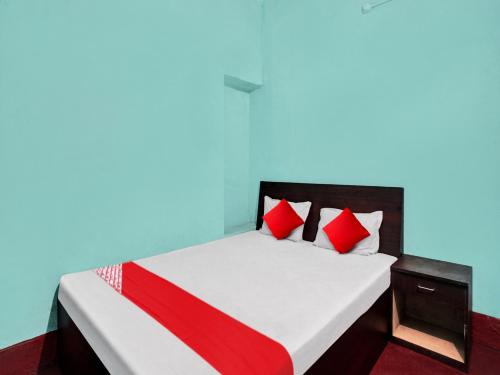 OYO Flagship New Pushpanjali Guest House في باتنا: غرفة نوم بسرير ومخدات حمراء