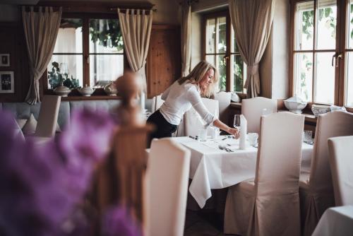 a woman is setting a table in a restaurant at Hotel Schönblick in Rodengo