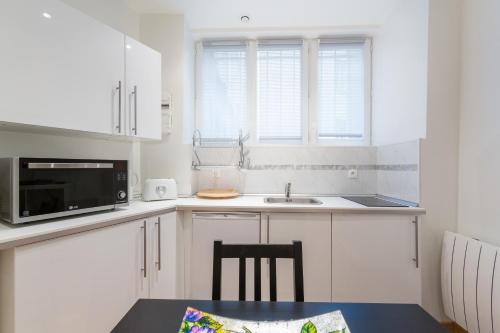 une cuisine blanche avec un évier et un micro-ondes dans l'établissement Appartement Petits Champs II, à Paris