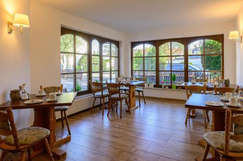 um restaurante com mesas e cadeiras e janelas grandes em Pension Heinrich Heine em Wittenberg