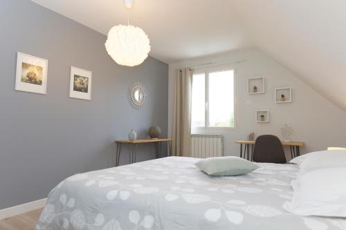 - une chambre blanche avec un grand lit et un lustre dans l'établissement Escapade en Normandie, à Barneville-sur-Seine