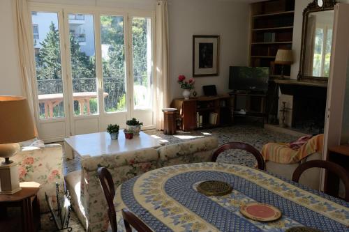 een woonkamer met een tafel, stoelen en ramen bij Maison calme avec piscine près de Cassis in Carnoux