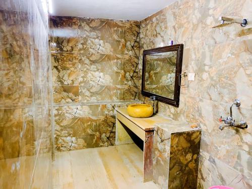 uma casa de banho em pedra com um lavatório e um espelho em Serendipity desert Camp in Thar Desert em Jaisalmer