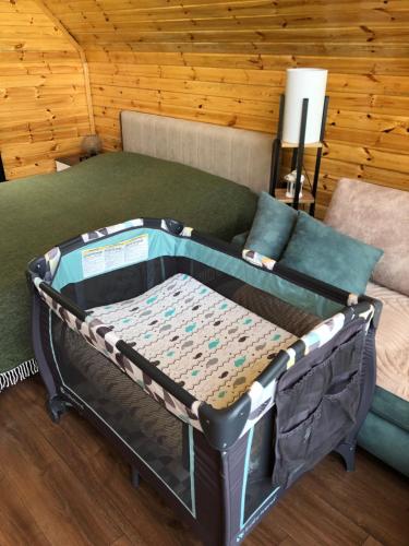 a crib in a room with a bed and a couch at WOOD HOUSE LAGODEKHI in Lagodekhi