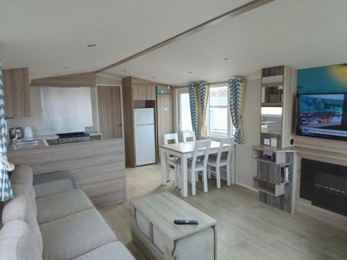 a living room with a couch and a table and a kitchen at Spacious Comfortable Surf Shack Caravan 35 x 12ft with Sea View Haven Littlesea Weymouth in Weymouth