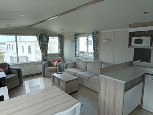 a living room with a couch and a table at Spacious Comfortable Surf Shack Caravan 35 x 12ft with Sea View Haven Littlesea Weymouth in Weymouth