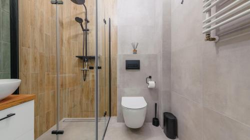 a bathroom with a toilet and a glass shower at Apartamenty Sun & Snow Morelowa in Władysławowo
