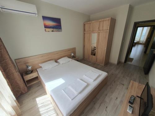 um quarto com uma cama branca e piso em madeira em Таня 8 em Pomorie