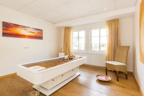 a white bedroom with a large bed and a chair at Hotel Deimann in Schmallenberg