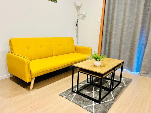 a yellow couch in a living room with a table at Modern Comfy 3 Bedrooms House in Chartwell in Hamilton