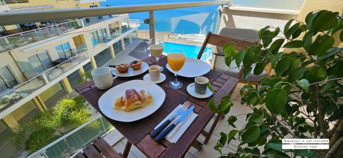 een tafel met twee borden eten op een balkon bij Sesimbra Cliffs OceanView - 5min walk to Beach in Sesimbra