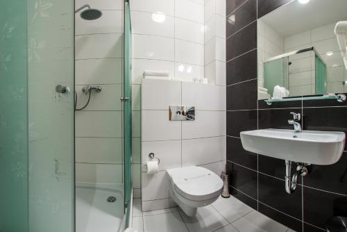 a bathroom with a toilet and a sink and a shower at Hotel Polonia in Biała Podlaska