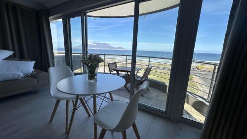 Zimmer mit einem Tisch und Stühlen sowie Meerblick in der Unterkunft Oceansnest Guest House in Bloubergstrand