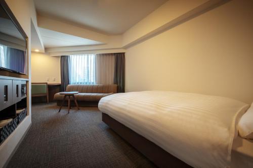 a hotel room with a bed and a couch at Dormy Inn Morioka in Morioka