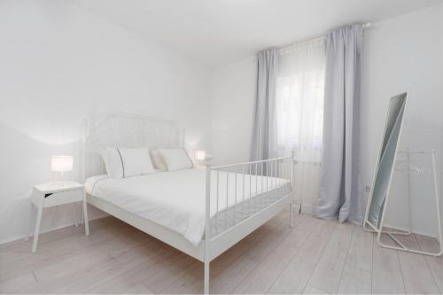 Villa Aria private Pool near Vrsar في فيرسار: غرفة نوم بيضاء مع سرير أبيض ونافذة
