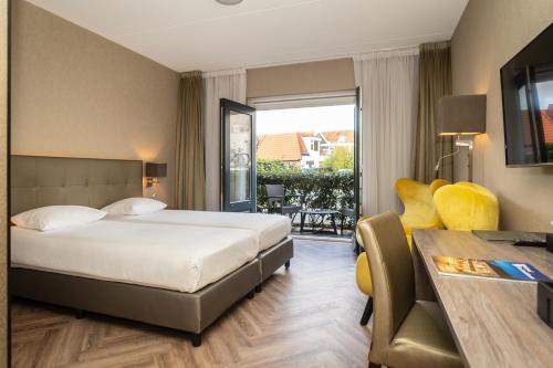 Habitación de hotel con cama y balcón en Hotel De Lindeboom en Den Burg