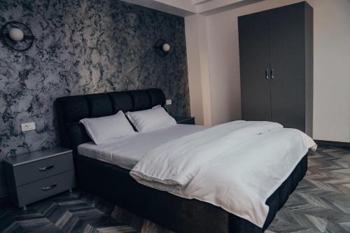 Schlafzimmer mit einem großen Bett mit einem schwarzen Kopfteil in der Unterkunft Pensiunea R&R Băilești in Băileşti