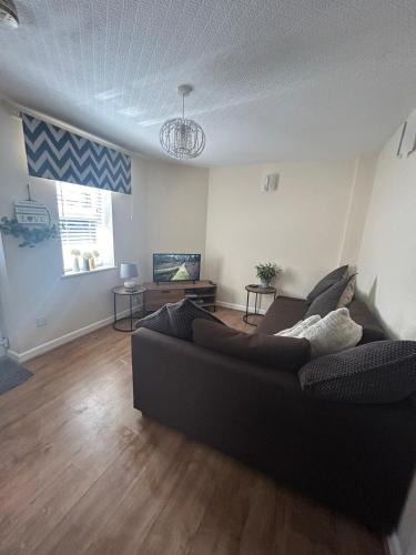 a living room with a black couch and wooden floors at Turnstone in Seaton