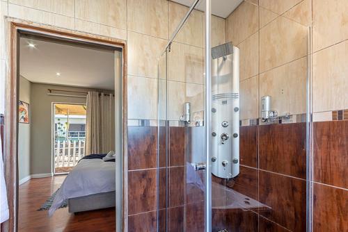 a bathroom with a glass shower and a bed at Botle Ba Afrika Lodge in Vereeniging