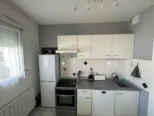 une cuisine avec des armoires blanches et un réfrigérateur blanc dans l'établissement Apt Albi 2 chambres climatisé plein centre et parking, à Albi