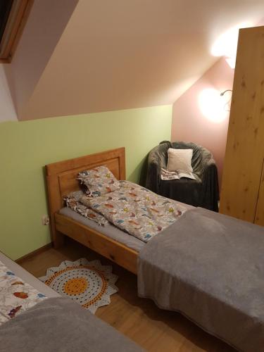 a bedroom with two beds and a chair at Agroturystyka Gandelinka Park Kędrzyno in Kędrzyno