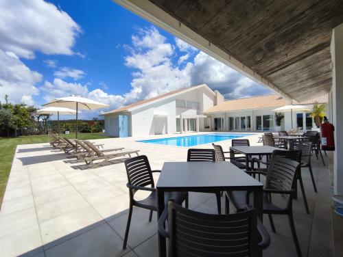 un patio con mesas y sillas junto a una piscina en NR Suites en Mealhada