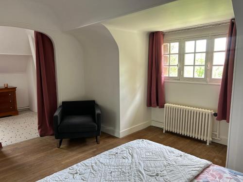 a bedroom with a chair and a bed and a window at LE PARC in Coulanges-sur-Yonne