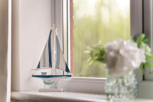 a toy boat on a window sill with a vase of flowers at Comfortable and Spacious Superb Holiday Home in Llanelli, Dog Friendly in Llanelli