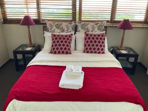 - une chambre dotée d'un grand lit avec des oreillers rouges et blancs dans l'établissement Jopasso Guest House, à Pretoria