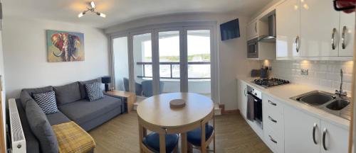 a kitchen and living room with a couch and a table at Stylish Saundersfoot Top Floor 2-Bed Seaview Apartment, Balcony & Parking in Pembrokeshire