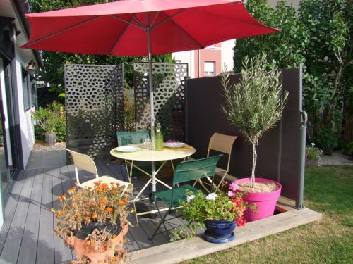 a patio with a table and a red umbrella at Le Chalet des Fanières in Chartres