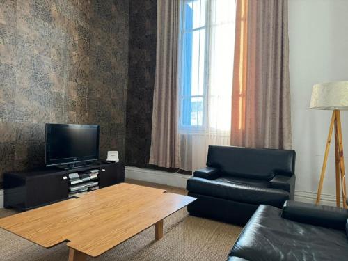 een woonkamer met een bank, een tv en een tafel bij Bel appartement in Tunis