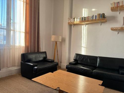 een woonkamer met een zwarte leren bank en een tafel bij Bel appartement in Tunis