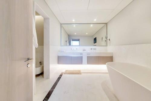 a white bathroom with a tub and a sink at Splendor 1BR with Breathtaking Palm Views in Dubai