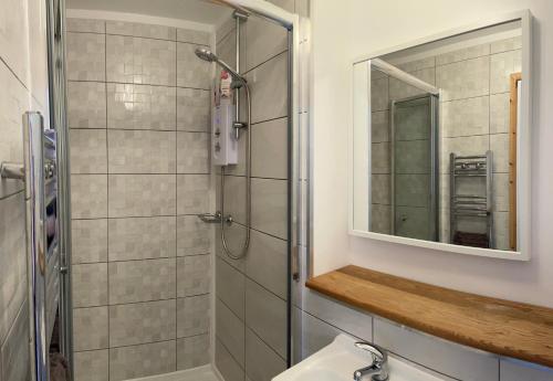 a bathroom with a shower and a sink and a mirror at Stylish Saundersfoot Top Floor 2-Bed Seaview Apartment, Balcony & Parking in Pembrokeshire
