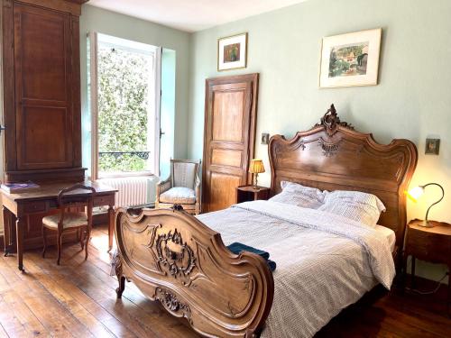 1 dormitorio con cama de madera, escritorio y ventana en Grande et belle demeure en Prez-sous-Lafauche