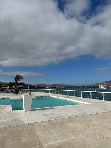 a swimming pool next to a fence and the ocean at Sharksproperties Apartment in Mindelo