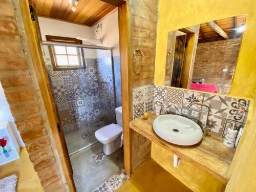 Un baño con lavabo y ducha con inodoro. en Chalé Pedra Chanfrada 02, en Gonçalves