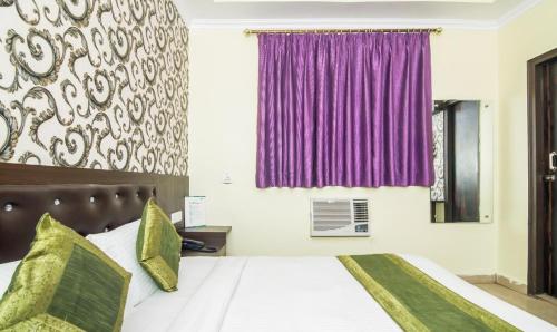 a bedroom with a large bed with purple curtains at Hotel Pacific Blu in Lucknow
