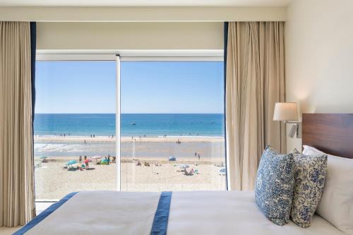 Residence Sol e Mar في ساليما: غرفة نوم بسرير وإطلالة على شاطئ