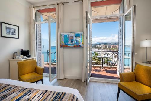 1 dormitorio con 1 cama y 2 sillas y balcón en Hotel Suisse, en Niza