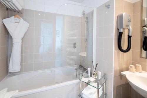 a bathroom with a tub and a sink and a phone at Hotel Suisse in Nice