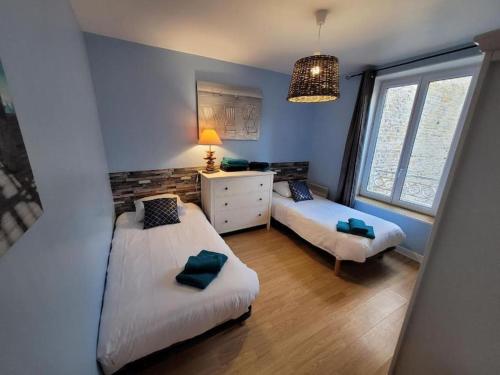 a bedroom with two beds and a dresser and a window at Beach House & Patio by Melrose in Arromanches-les-Bains