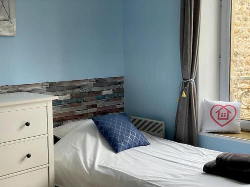 a bedroom with a bed with a blue wall at Beach House & Patio by Melrose in Arromanches-les-Bains