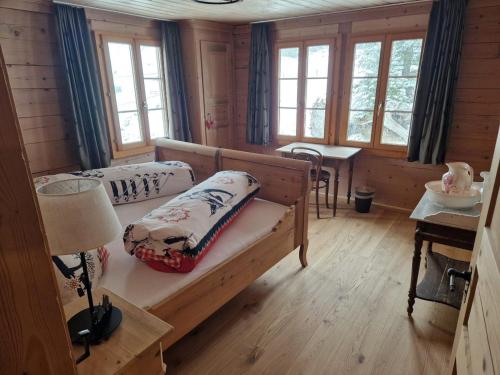 a bedroom with two beds and a table and windows at Alpenruh Kiental in Griesalp