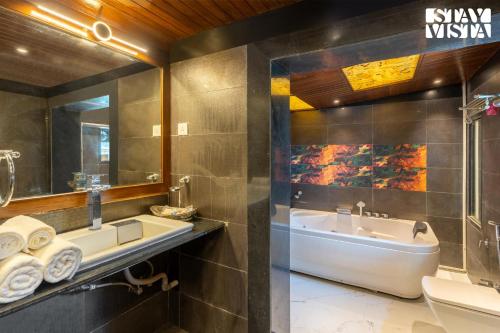 a bathroom with a sink and a tub and a toilet at StayVista's Grace & Light - Hill-view villa with Outdoor pool, Terrace & Games room in Panchgani