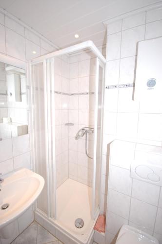 baño blanco con ducha y lavamanos en Ferienwohnung Petunie, en Altenau