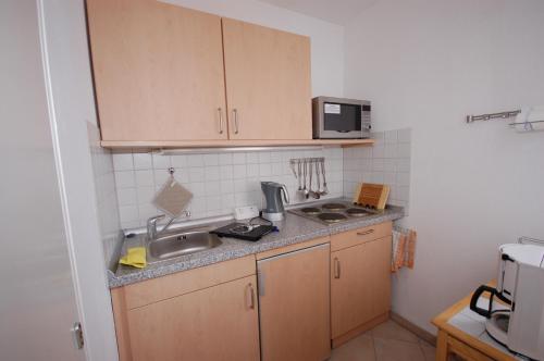 una pequeña cocina con fregadero y microondas en Ferienwohnung Petunie en Altenau