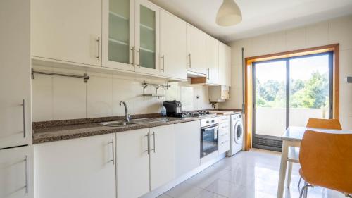 a kitchen with white cabinets and a sink at Seaside Retreat T2 by LovelyStay in Arcozelo